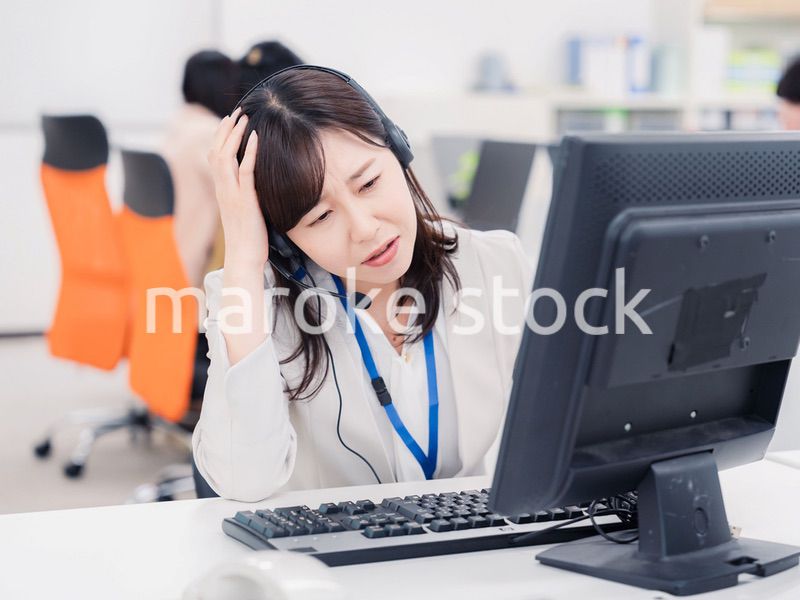 電話対応で疲労するお客様センターの女性