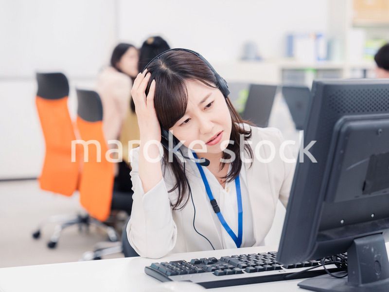 電話対応で疲労するお客様センターの女性
