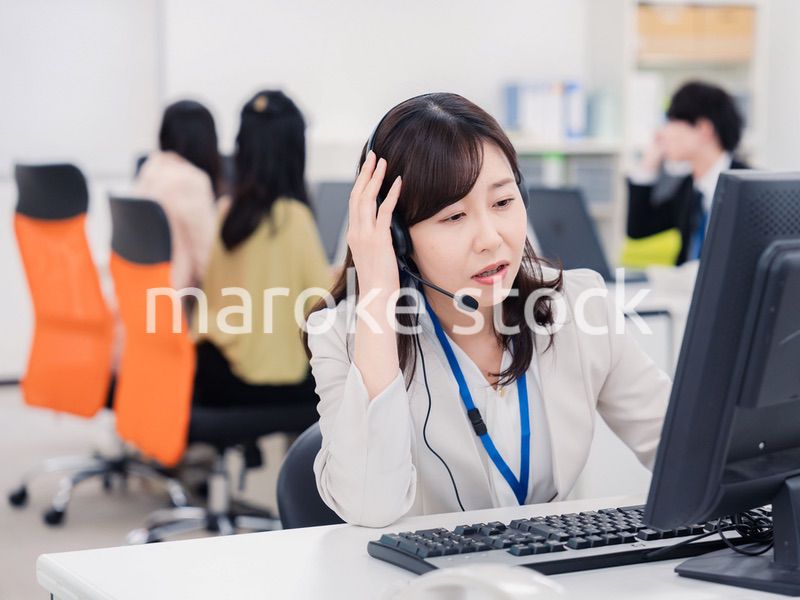 電話対応で疲労するお客様センターの女性