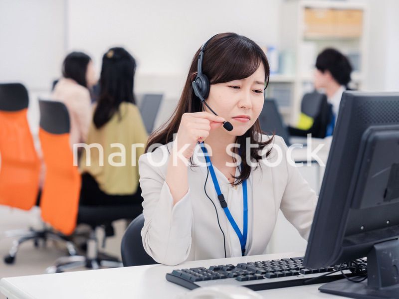 電話対応で疲労するお客様センターの女性
