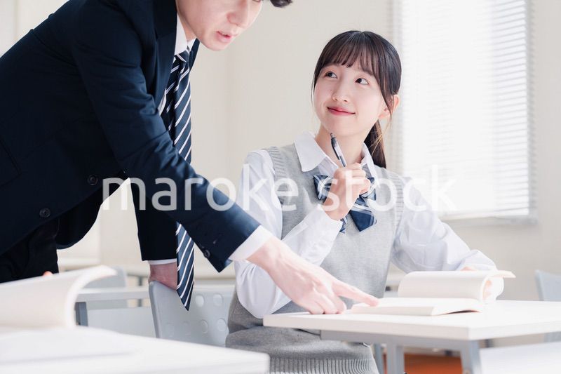 教室で先生に質問をする女子高生