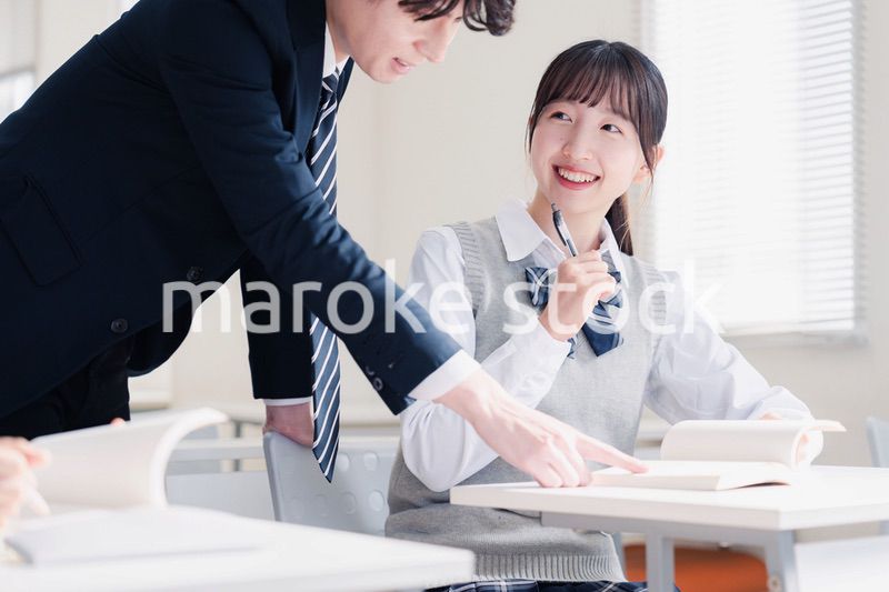 教室で先生に質問をする女子高生