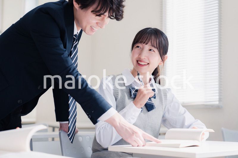 教室で先生に質問をする女子高生