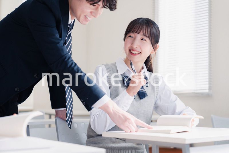 教室で先生に質問をする女子高生