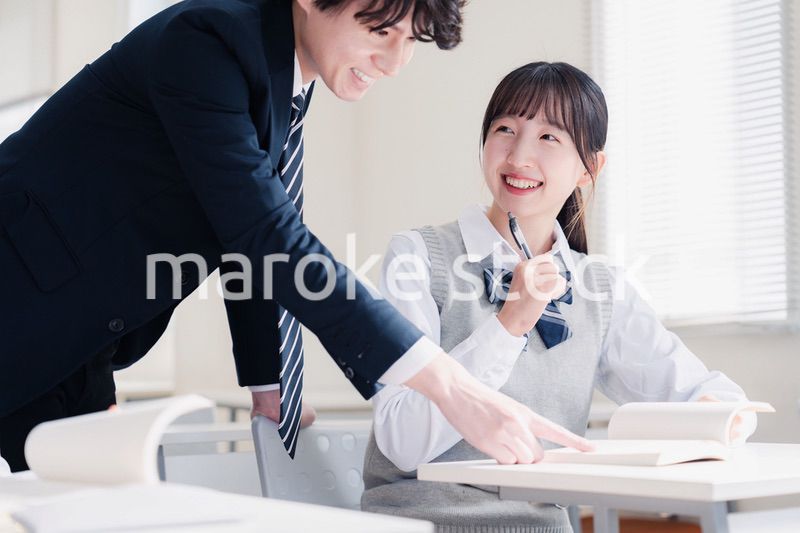 教室で先生に質問をする女子高生