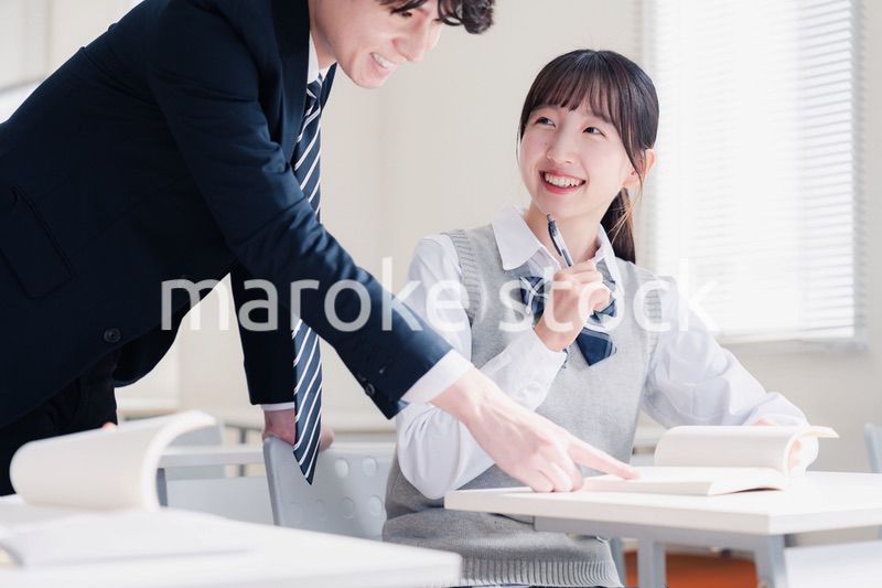 教室で先生に質問をする女子高生