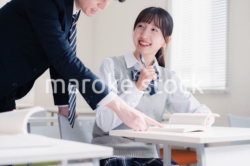 教室で先生に質問をする女子高生