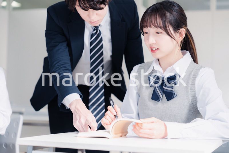 教室で先生に質問をする女子高生