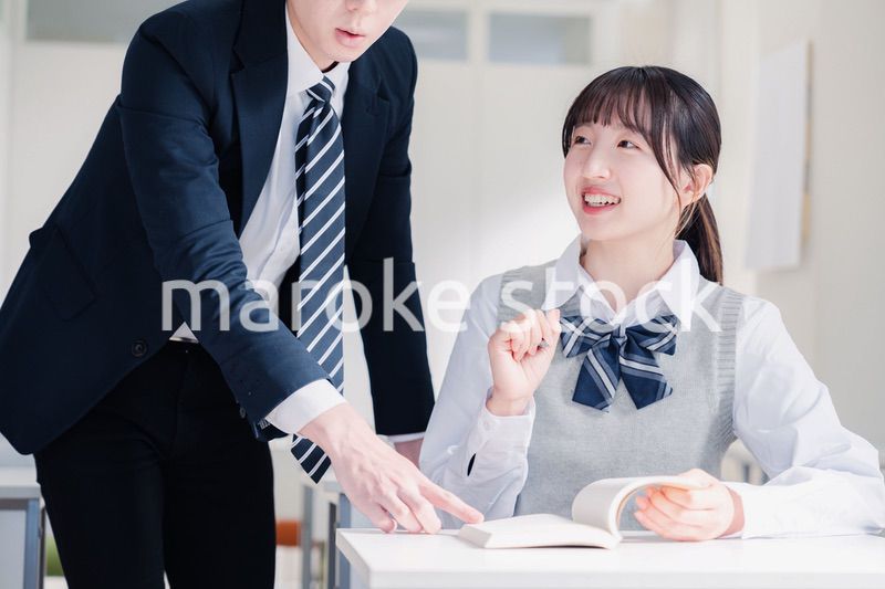 教室で先生に質問をする女子高生