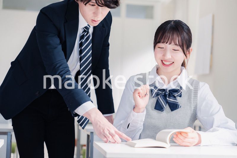 教室で先生に質問をする女子高生