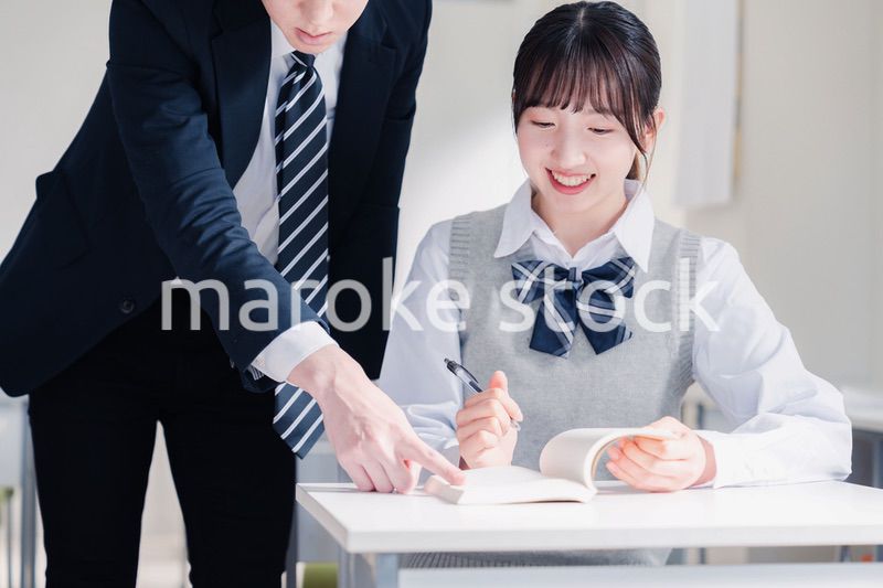 教室で先生に質問をする女子高生