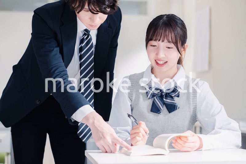 教室で先生に質問をする女子高生