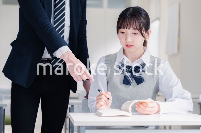 教室で先生に質問をする女子高生
