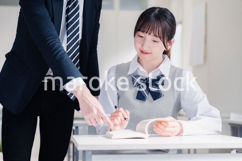 教室で先生に質問をする女子高生