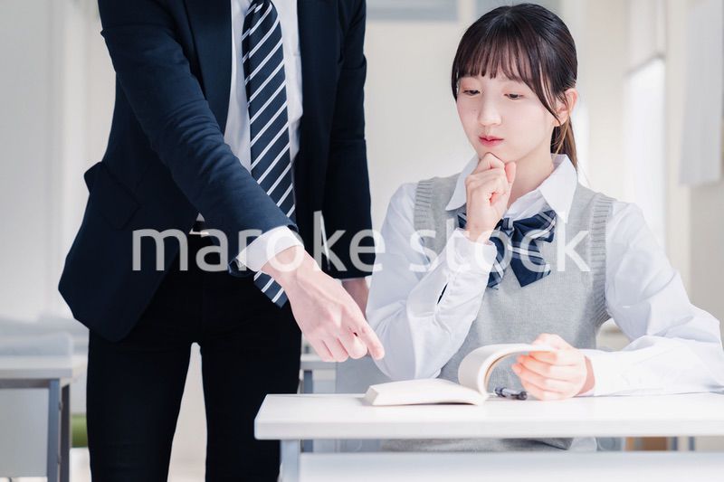 教室で先生に質問をする女子高生