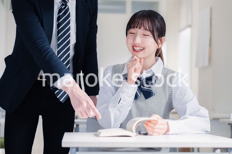 教室で先生に質問をする女子高生