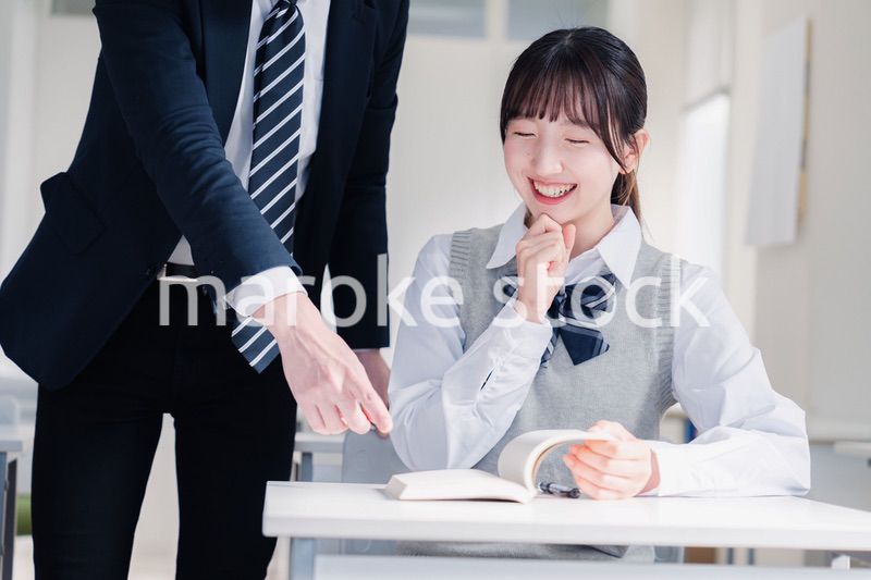教室で先生に質問をする女子高生