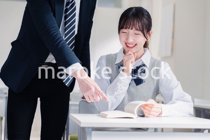 教室で先生に質問をする女子高生