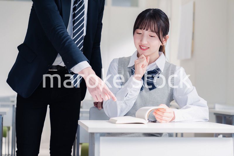 教室で先生に質問をする女子高生
