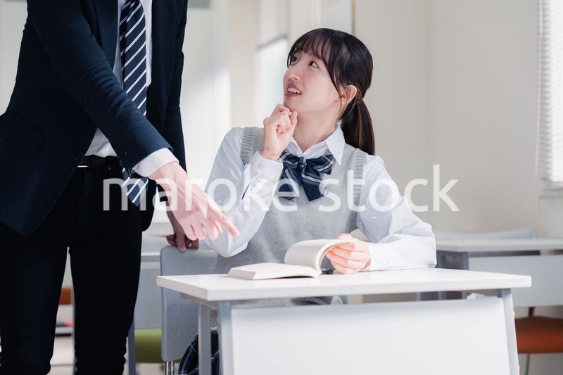 教室で先生に質問をする女子高生