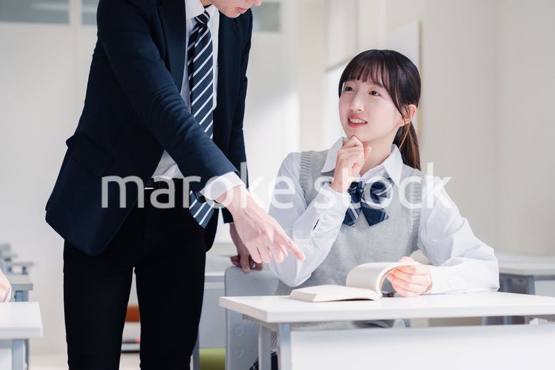 教室で先生に質問をする女子高生