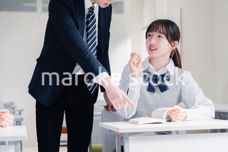 教室で先生に質問をする女子高生