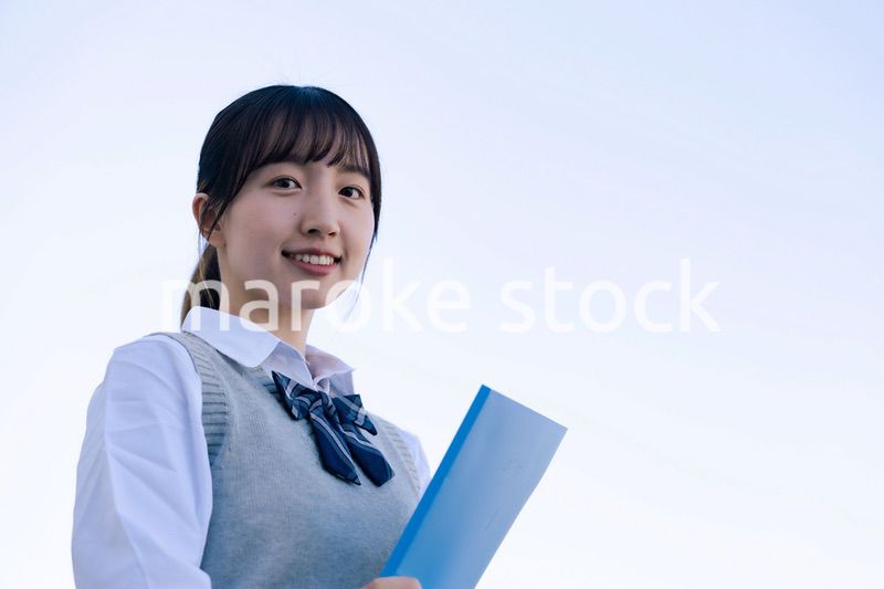 外で遠くを見る制服を着た女子高生