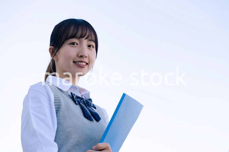 外で遠くを見る制服を着た女子高生