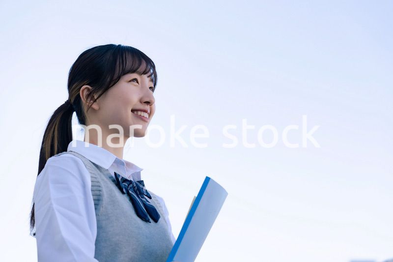 外で遠くを見る制服を着た女子高生
