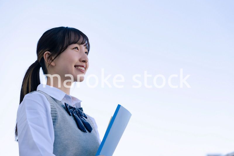 外で遠くを見る制服を着た女子高生