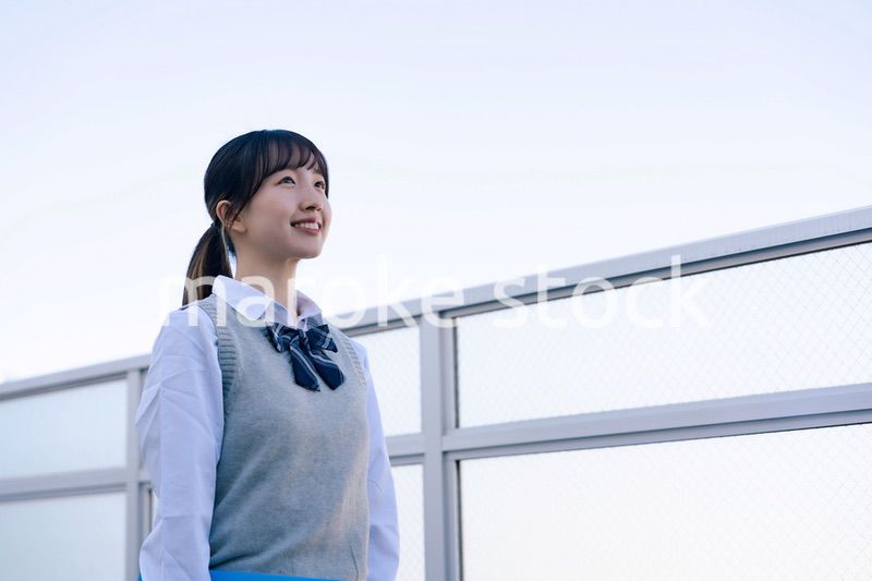 外で遠くを見る制服を着た女子高生