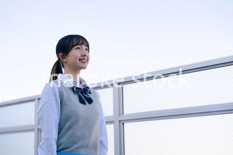 外で遠くを見る制服を着た女子高生