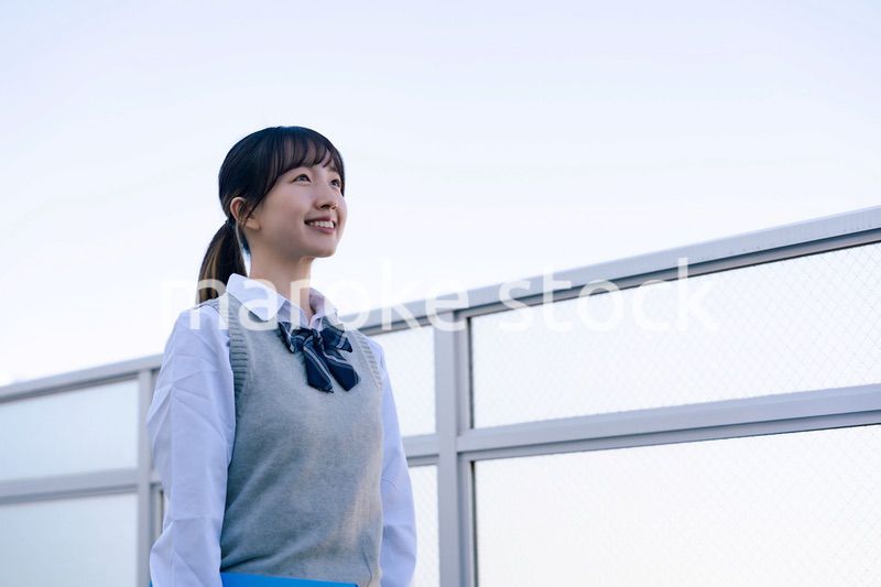 外で遠くを見る制服を着た女子高生