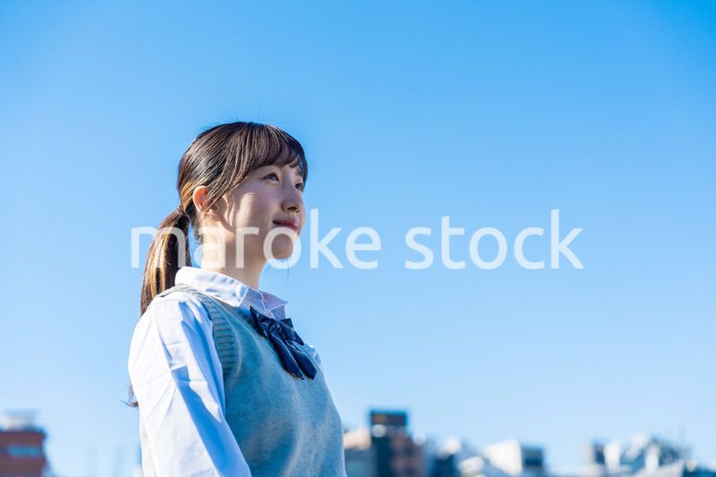 外で遠くを見る制服を着た女子高生