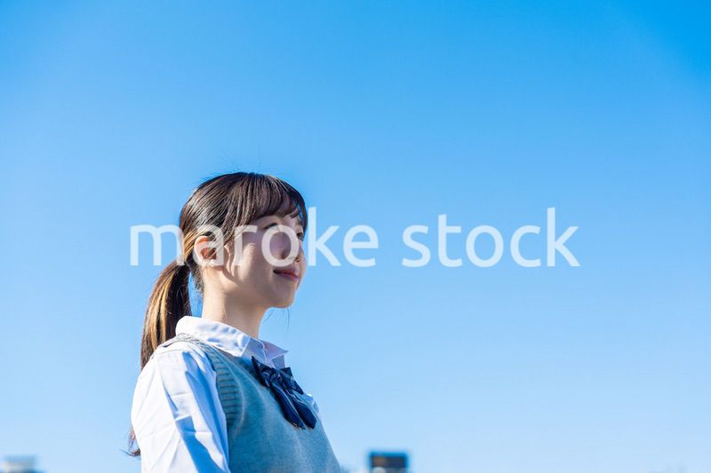 外で遠くを見る制服を着た女子高生
