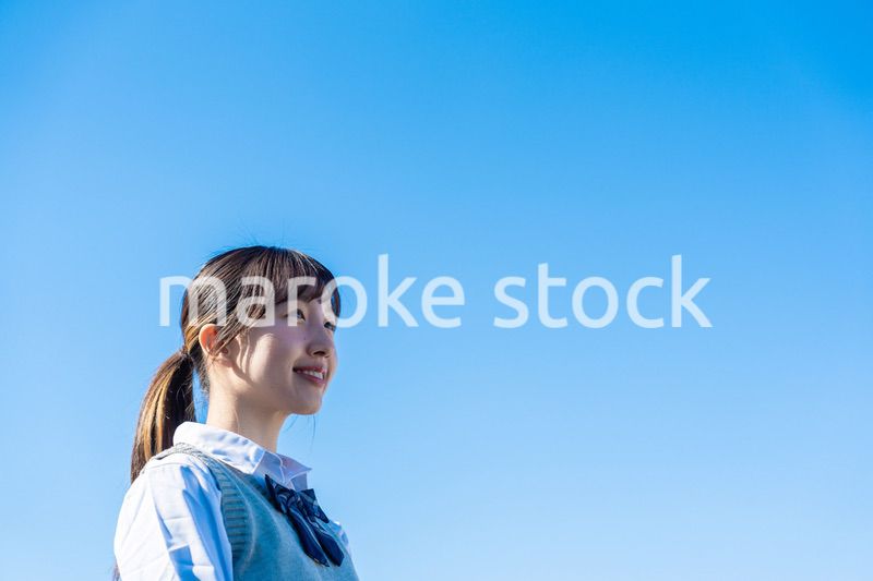 外で遠くを見る制服を着た女子高生