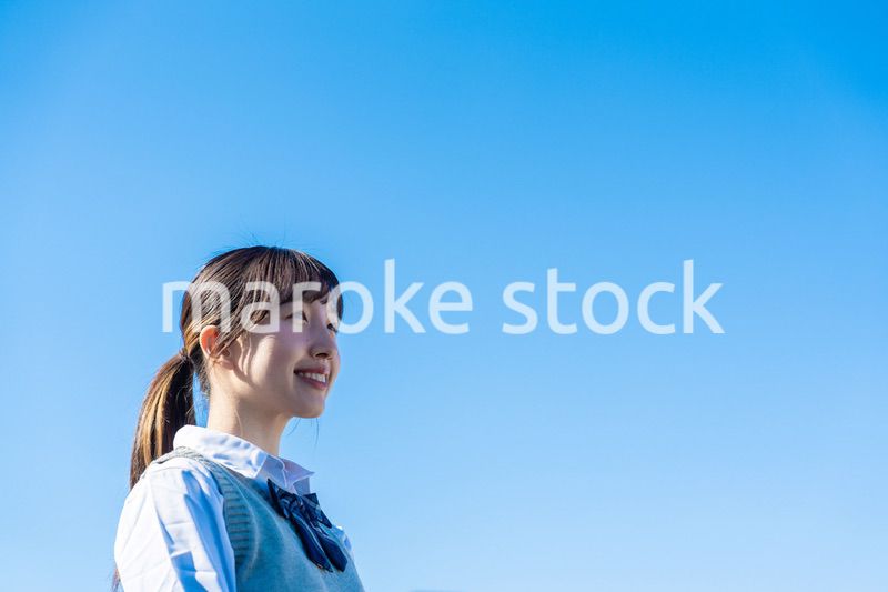 外で遠くを見る制服を着た女子高生