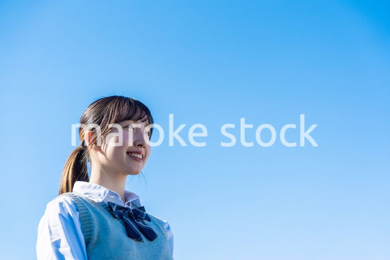 外で遠くを見る制服を着た女子高生