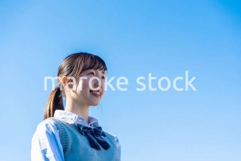 外で遠くを見る制服を着た女子高生
