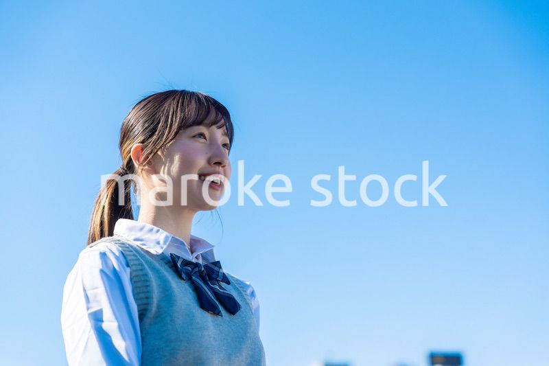外で遠くを見る制服を着た女子高生