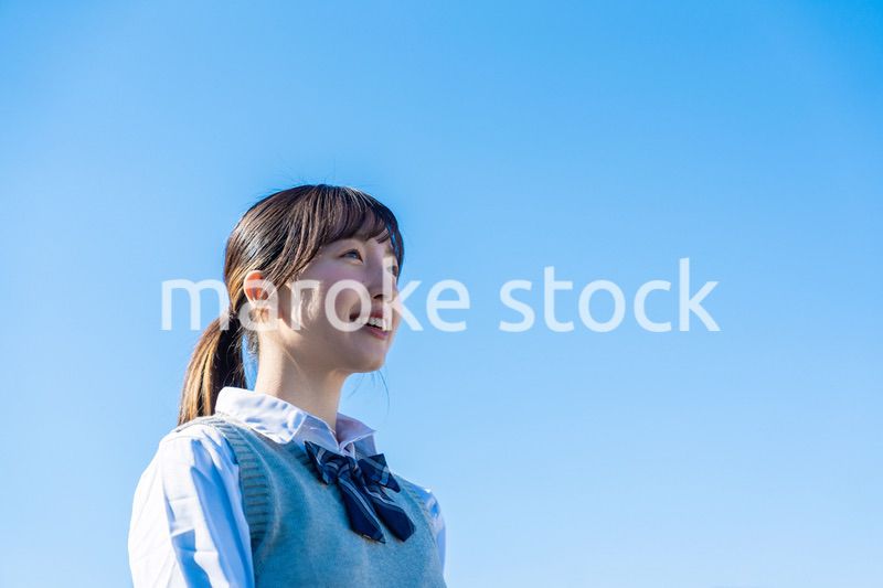 外で遠くを見る制服を着た女子高生
