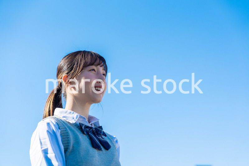 外で遠くを見る制服を着た女子高生