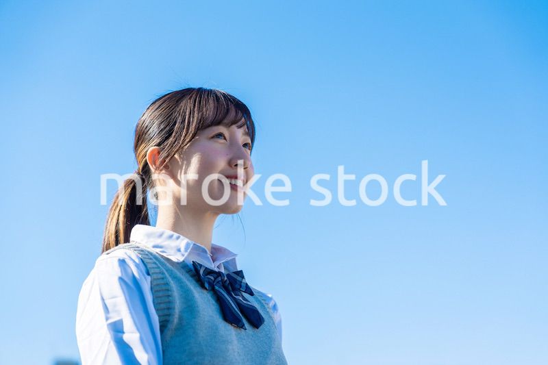 外で遠くを見る制服を着た女子高生