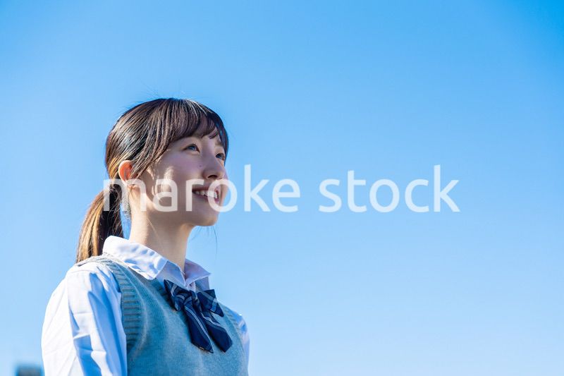 外で遠くを見る制服を着た女子高生
