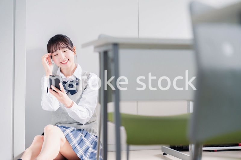 教室で笑顔でスマホを使う女子高生