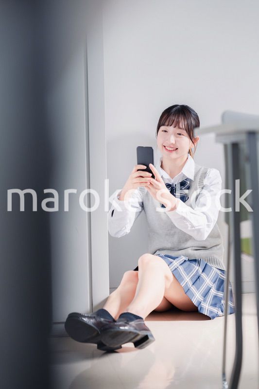 教室で笑顔でスマホを使う女子高生