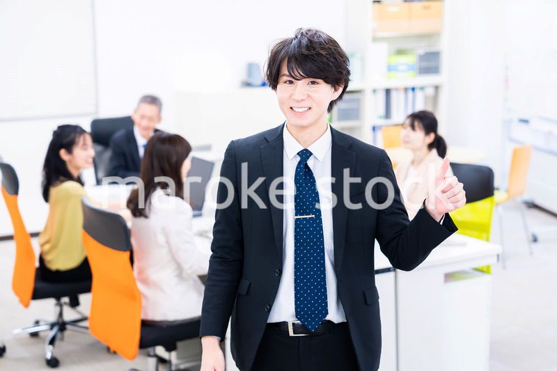 笑顔でグッドサインをする若いビジネスマン