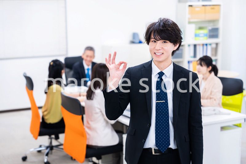 笑顔でグッドサインをする若いビジネスマン