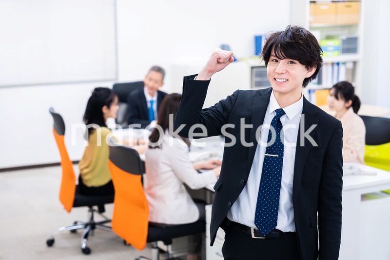 笑顔でガッツポーズをする若いビジネスマン