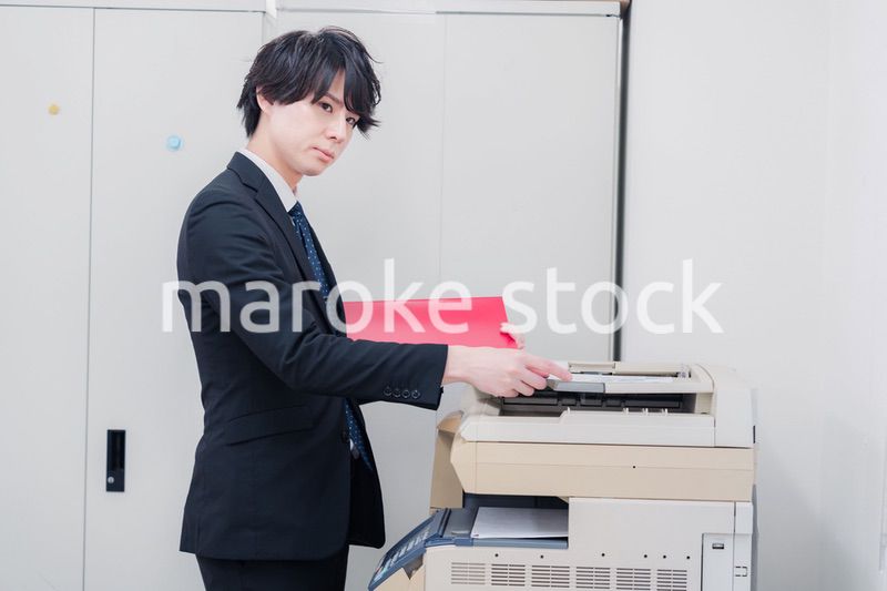 オフィスでコピーを取るスーツを着た男性